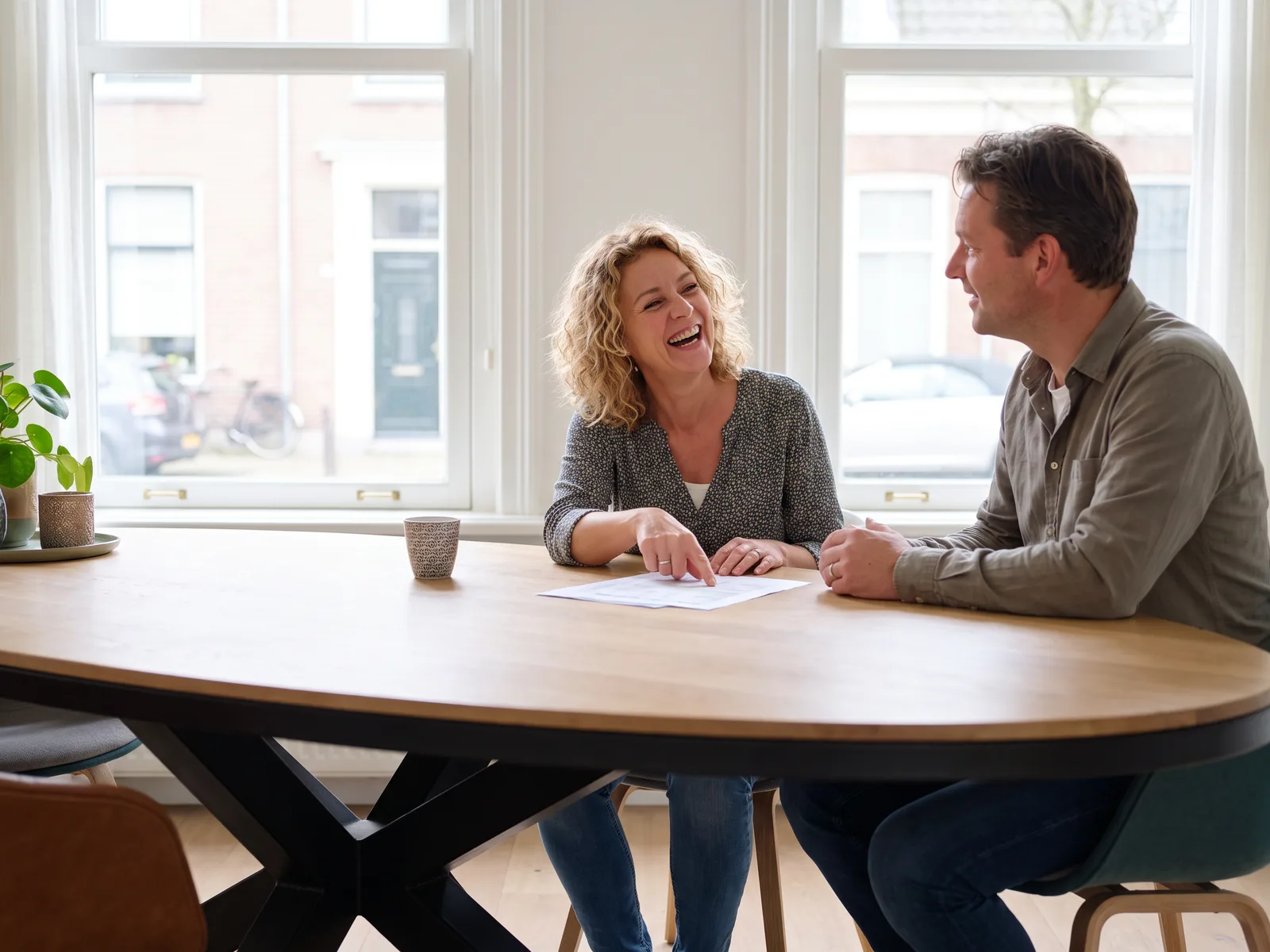 Een stel bespreekt aan hun eettafel de begroting van hun verbouwing met een adviseur van ons