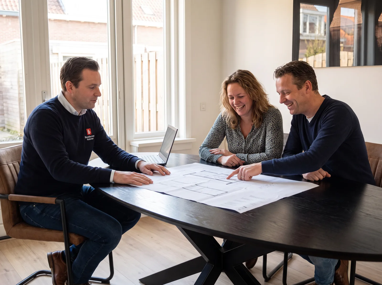 Een adviseur van ons bespreekt aan tafel de tekeningen van een opbouw met de bewoners