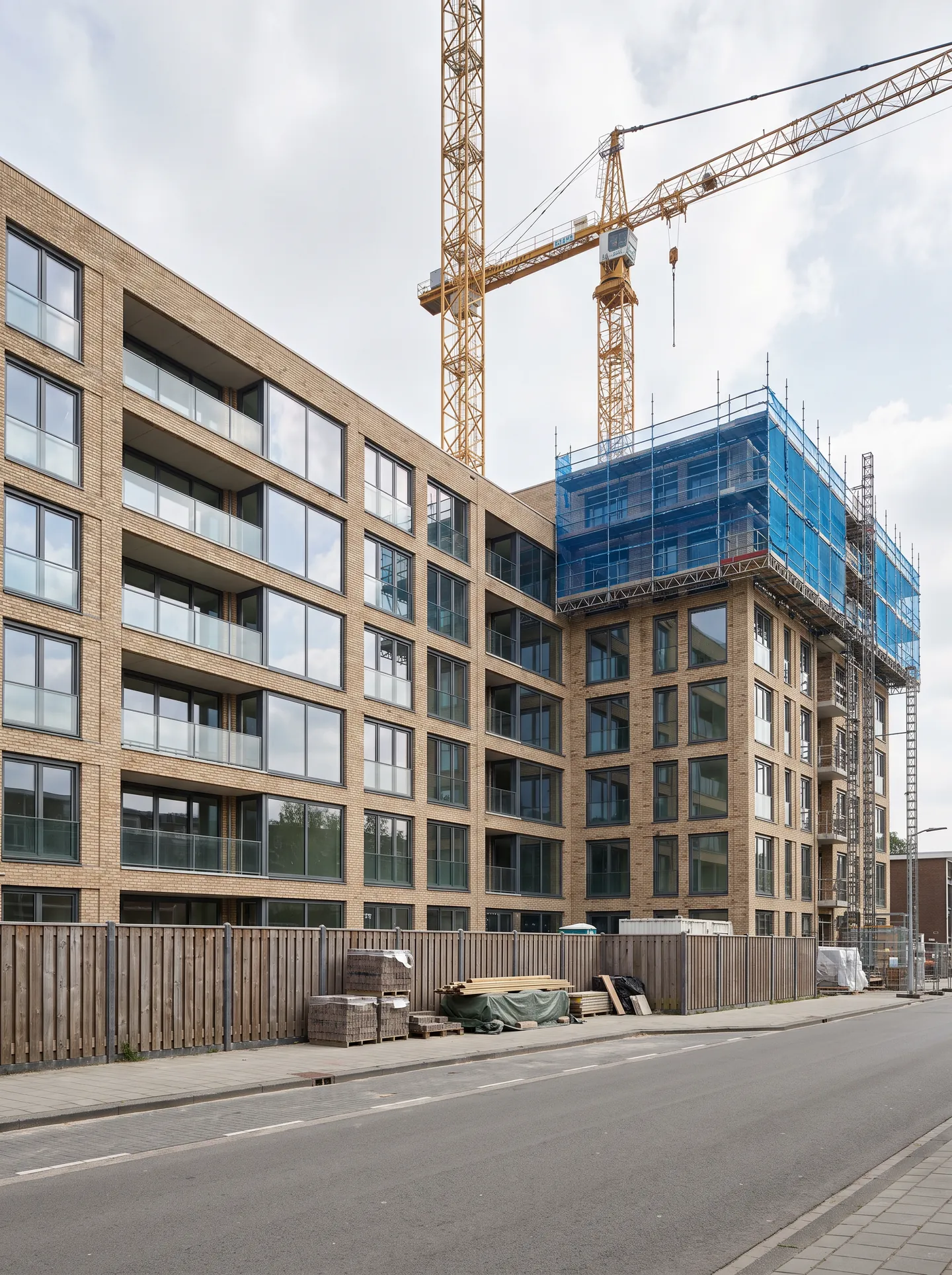 Een nieuw appartementencomplex in de afbouw, met steigers en een torenkraan