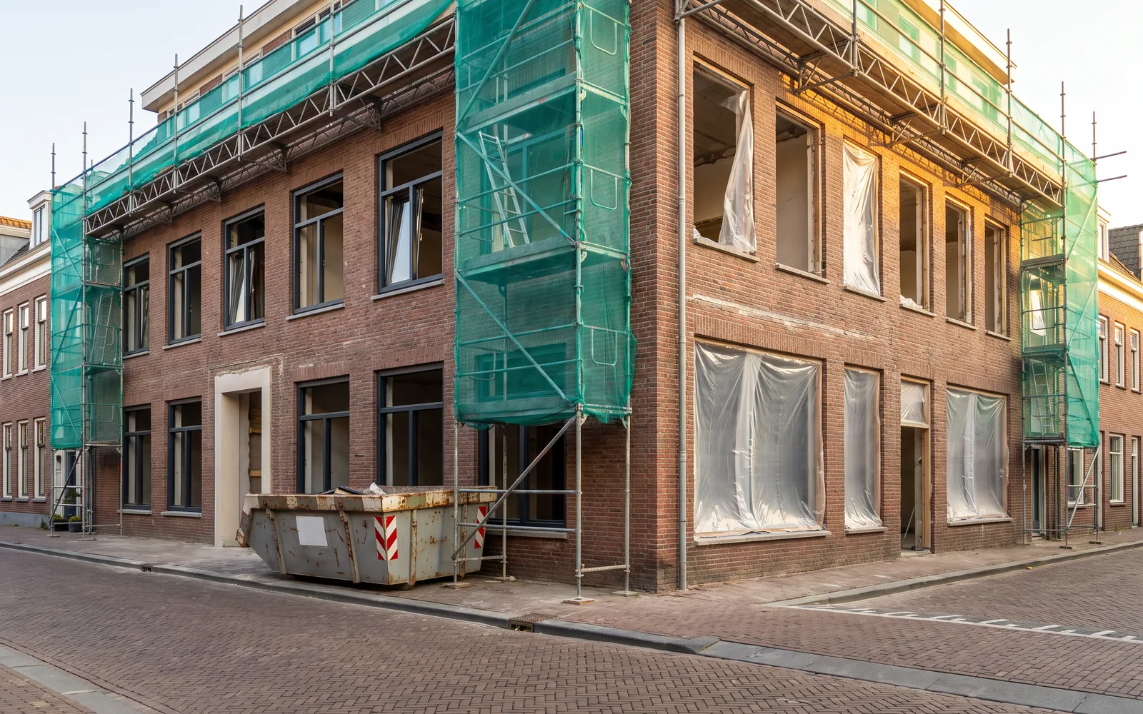 Bouwplaats van een verbouwing die halverwege is, met steigers langs de gevel