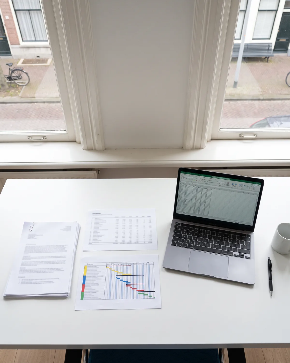 Uitgeprinte stukken en een laptop met een overzicht op een bureau