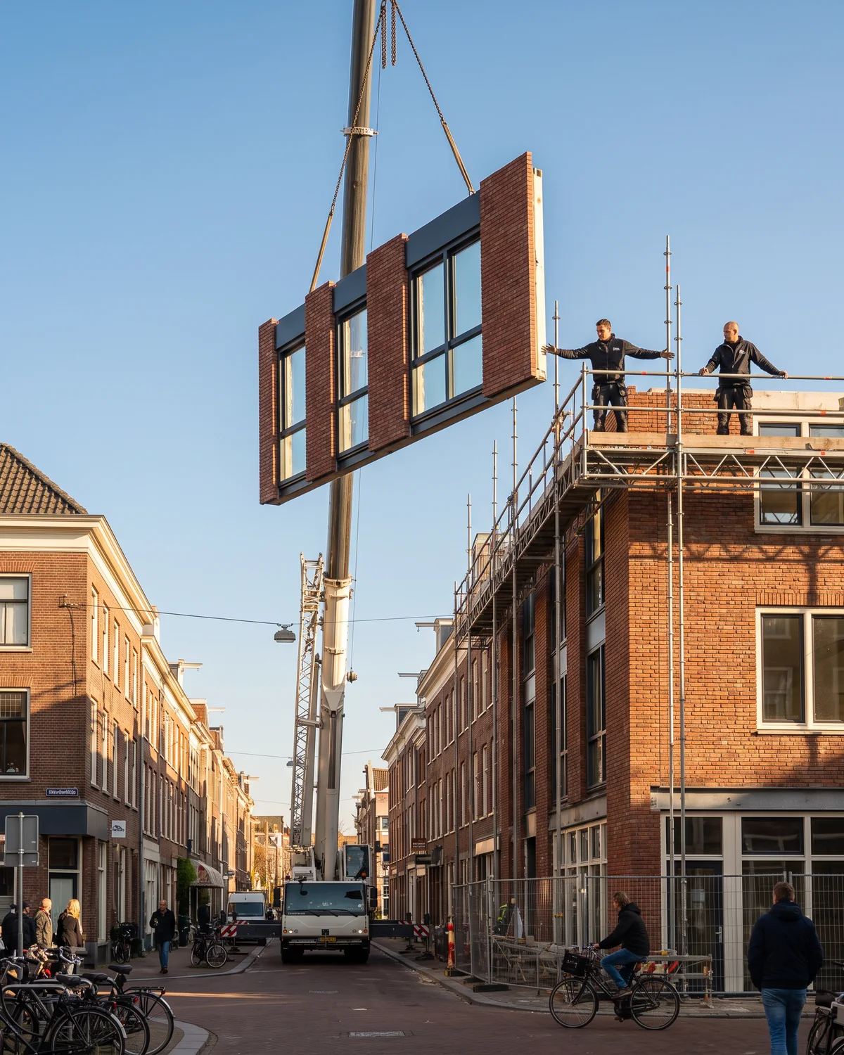 Prefab gevelelementen worden met een kraan op een verbouwd pand gezet